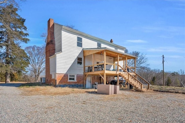 back of house featuring a deck, stairway, a chimney, and brick siding