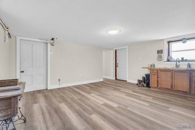 interior space with light wood-type flooring, visible vents, and baseboards