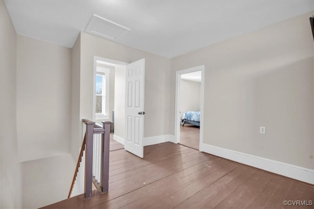 interior space featuring attic access, baseboards, an upstairs landing, and hardwood / wood-style flooring