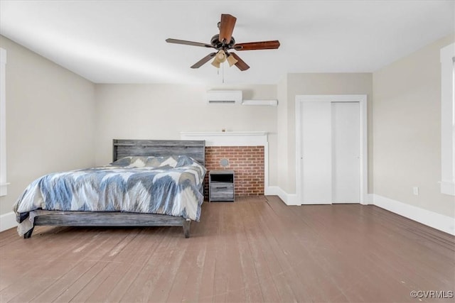 bedroom featuring a wall mounted AC, wood finished floors, and baseboards