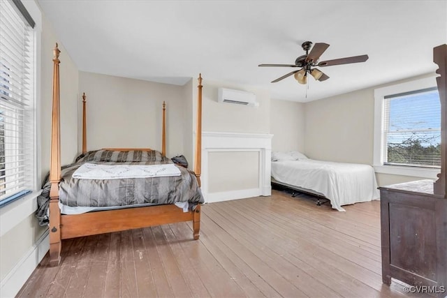 bedroom featuring wood-type flooring, ceiling fan, and an AC wall unit