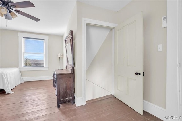 bedroom featuring hardwood / wood-style floors, a ceiling fan, and baseboards