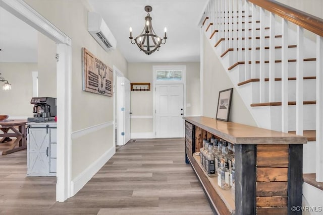 entryway featuring a wall unit AC, stairway, an inviting chandelier, and wood finished floors