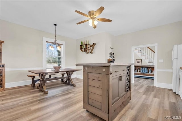 interior space with stairs, a ceiling fan, light wood-style flooring, and baseboards