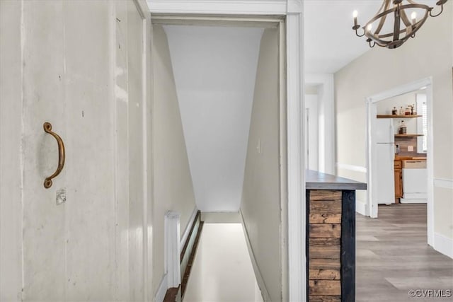 hall featuring an inviting chandelier and wood finished floors