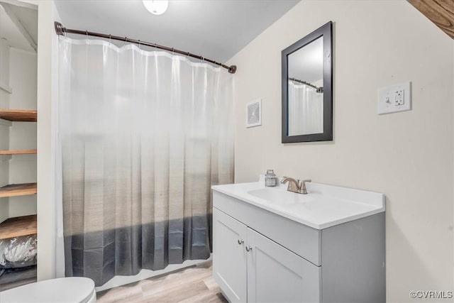 bathroom featuring curtained shower, visible vents, toilet, vanity, and wood finished floors