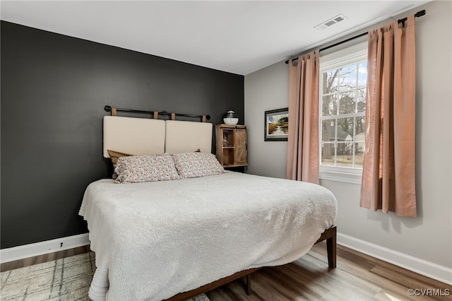 bedroom featuring wood finished floors, visible vents, and baseboards