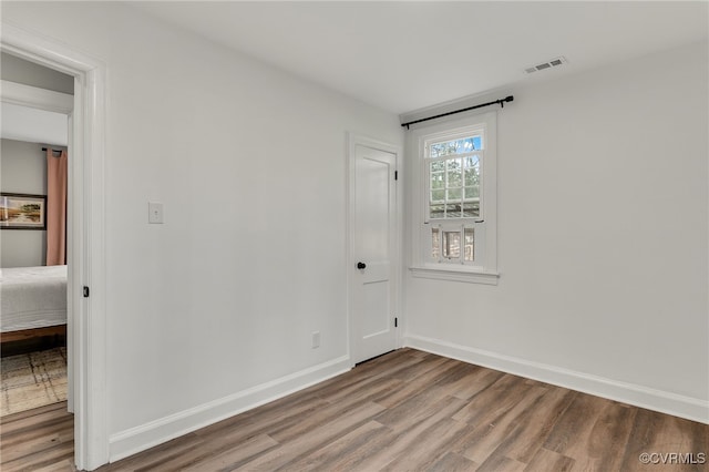 unfurnished room featuring visible vents, baseboards, and wood finished floors