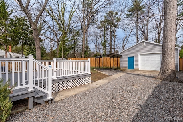 view of yard with a detached garage, an outbuilding, gravel driveway, fence, and a deck