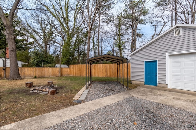 view of yard with a detached carport, driveway, and fence