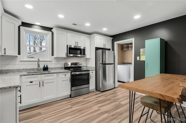 kitchen with light wood-style flooring, a sink, visible vents, white cabinets, and appliances with stainless steel finishes