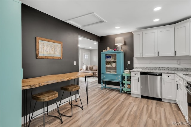 kitchen featuring recessed lighting, white cabinetry, light stone countertops, light wood-type flooring, and dishwasher