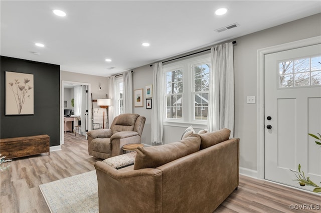 living area with light wood finished floors, plenty of natural light, visible vents, and recessed lighting