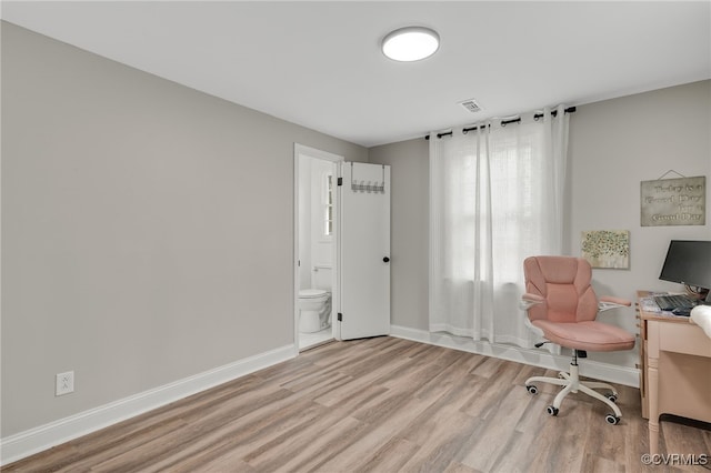 office space featuring baseboards, visible vents, and light wood finished floors