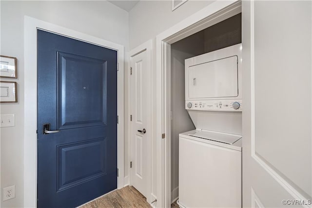 laundry room with stacked washer and dryer, laundry area, and wood finished floors