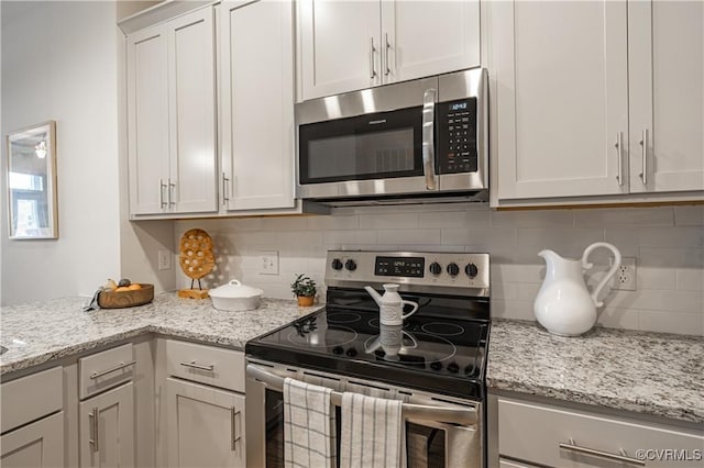 kitchen with light stone countertops, tasteful backsplash, and appliances with stainless steel finishes