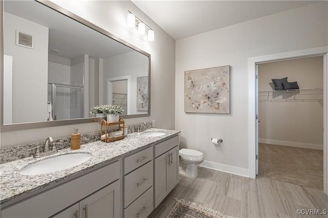 bathroom featuring a shower stall, a spacious closet, visible vents, and a sink