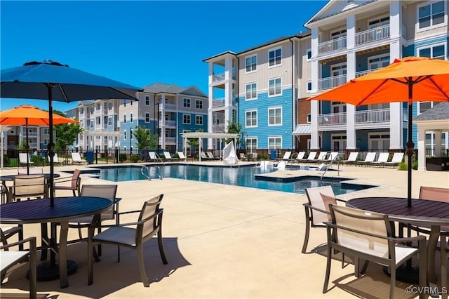 community pool featuring a residential view, fence, and a patio