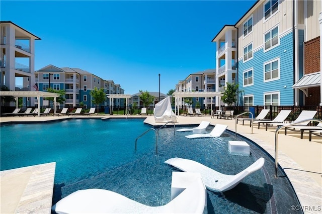 community pool with a residential view, fence, and a patio