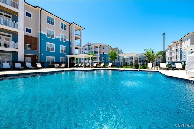 community pool featuring a residential view, fence, and a patio