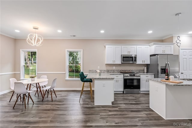 kitchen featuring appliances with stainless steel finishes, a breakfast bar, white cabinets, and a peninsula