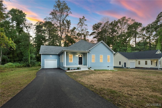 ranch-style home featuring a yard, aphalt driveway, and an attached garage