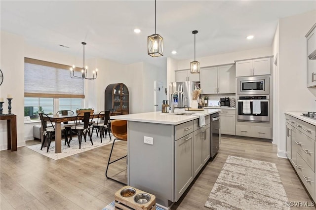 kitchen featuring light wood-type flooring, stainless steel appliances, light countertops, and gray cabinetry