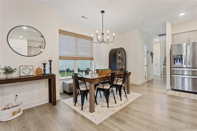 dining space with a chandelier, stairs, visible vents, and light wood-style floors