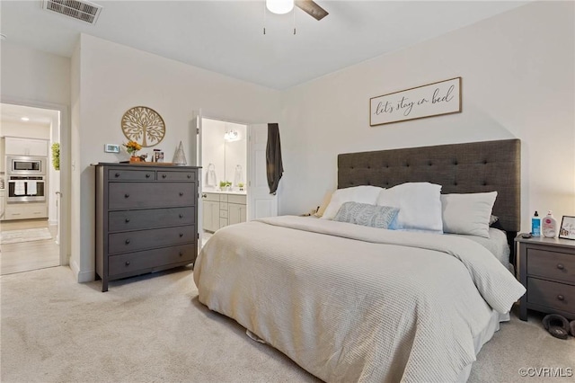 bedroom with ensuite bath, visible vents, a ceiling fan, and light colored carpet