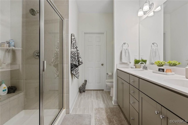 full bathroom with a stall shower, a sink, toilet, and double vanity