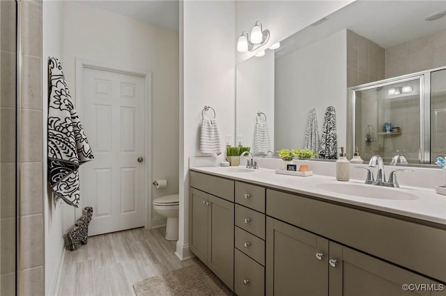 bathroom with double vanity, a stall shower, a sink, and toilet