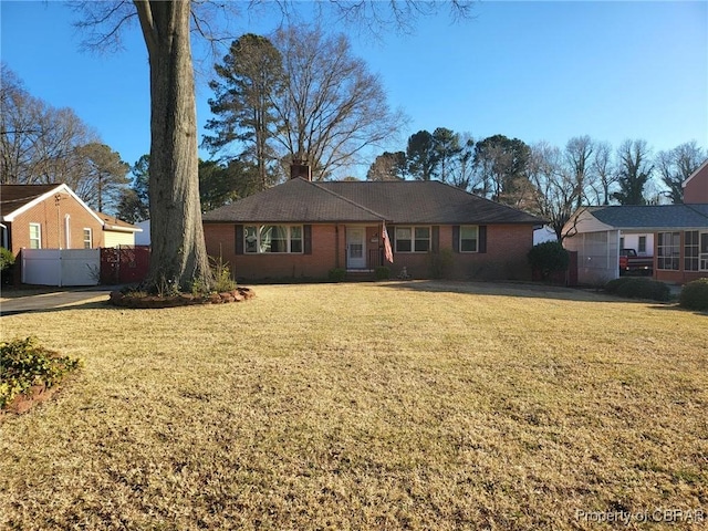 ranch-style home with a front yard, brick siding, fence, and a chimney