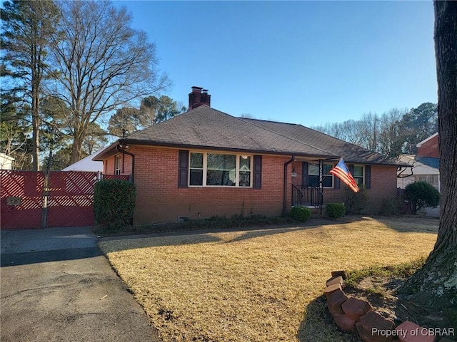 ranch-style house with brick siding, a shingled roof, fence, a front lawn, and a chimney