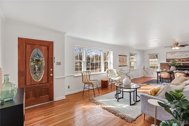 entrance foyer featuring ornamental molding, wood finished floors, a ceiling fan, and baseboards