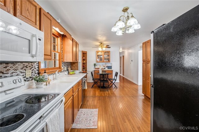 kitchen with white appliances, light wood-style floors, light countertops, backsplash, and brown cabinets