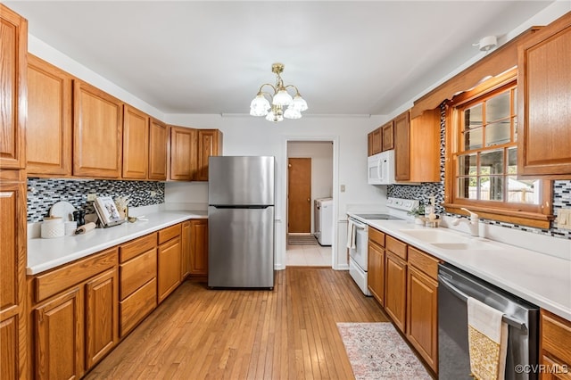 kitchen with appliances with stainless steel finishes, light countertops, light wood-style floors, a chandelier, and a sink