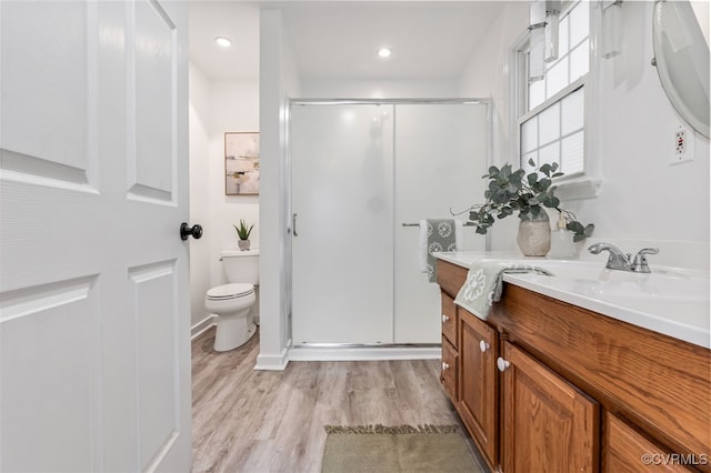 full bathroom featuring toilet, a shower stall, wood finished floors, and vanity