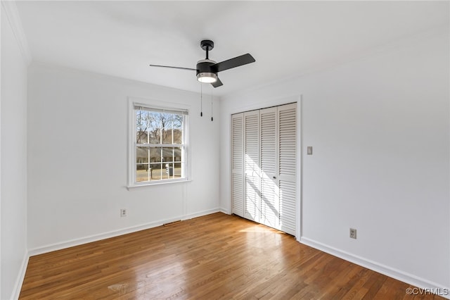 unfurnished bedroom with a ceiling fan, a closet, baseboards, and wood finished floors