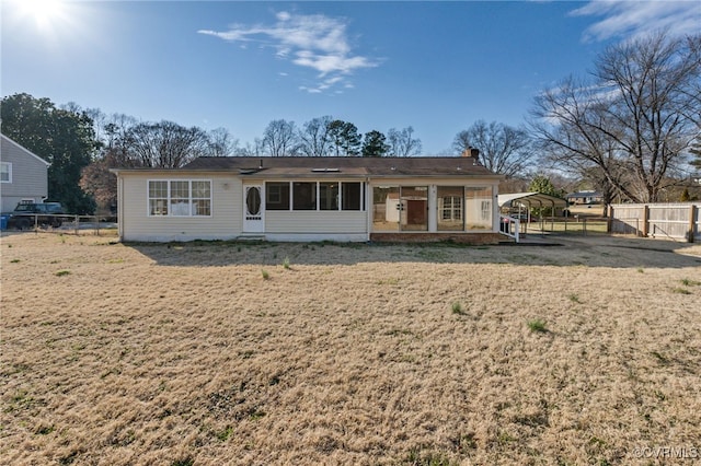 view of front of home featuring a front lawn, a chimney, fence, and a sunroom