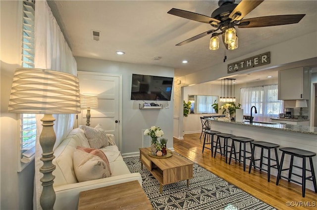 living area featuring baseboards, visible vents, a ceiling fan, wood finished floors, and recessed lighting