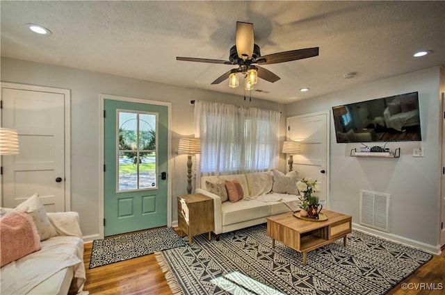 living room featuring recessed lighting, visible vents, a textured ceiling, wood finished floors, and baseboards