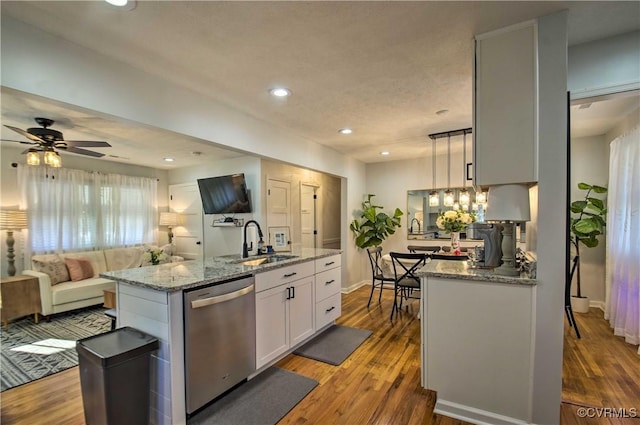 kitchen featuring light stone counters, dishwasher, a sink, and wood finished floors