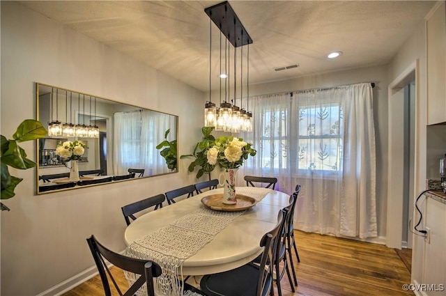 dining room with baseboards, wood finished floors, visible vents, and recessed lighting