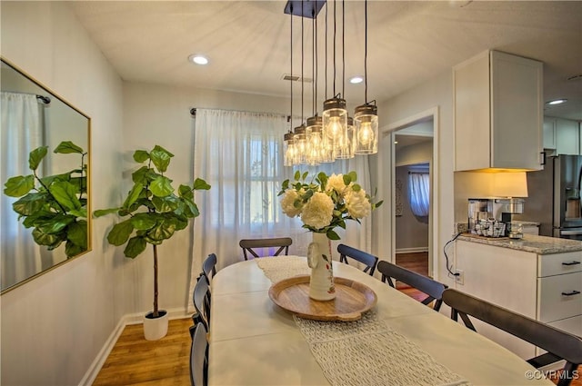 dining room with baseboards, wood finished floors, and recessed lighting