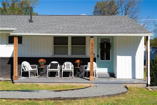 exterior space with roof with shingles, brick siding, and a patio