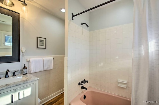 full bathroom with shower / tub combo with curtain, tile walls, wainscoting, vanity, and wood finished floors