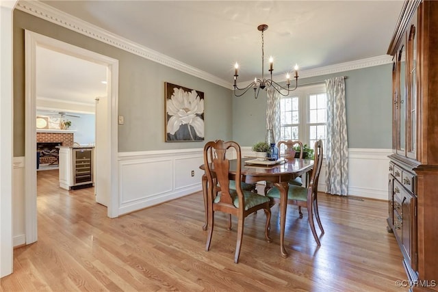 dining space with a chandelier, light wood-type flooring, a fireplace, and crown molding