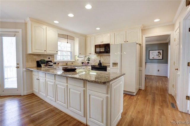 kitchen featuring ornamental molding, visible vents, a peninsula, and black appliances