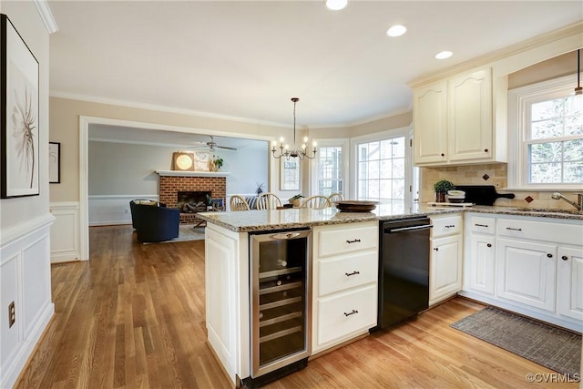 kitchen featuring a wainscoted wall, crown molding, a brick fireplace, beverage cooler, and a peninsula