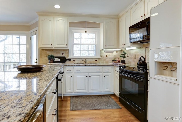 kitchen with light wood-style flooring, light stone countertops, crown molding, black appliances, and backsplash